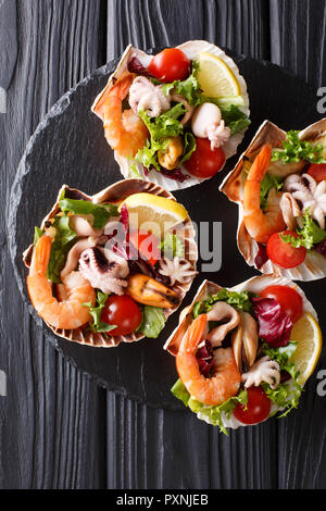 Gesunde snack Salat von Meeresfrüchten Shrimps, Tintenfische, Muscheln und Jakobsmuscheln sind in Muscheln in der Nähe serviert - auf den Tisch. Vertikal oben Ansicht von oben Stockfoto