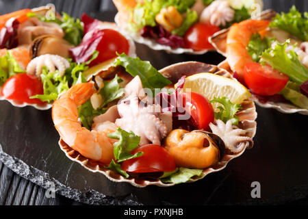 Gesunde snack Salat von Meeresfrüchten Shrimps, Tintenfische, Muscheln und Jakobsmuscheln sind in Muscheln in der Nähe serviert - auf den Tisch. Horizontale Stockfoto