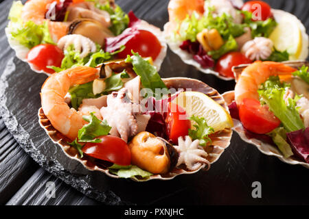 Frische Meeresfrüchte Salat mit Gemüse und Zitrone serviert im Seashells close-up auf dem Tisch. Horizontale Stockfoto