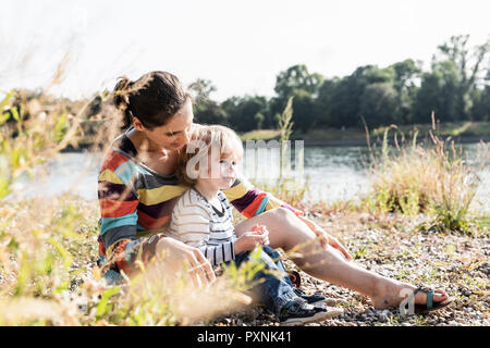 Mutter und Sohn am Fluss sitzen Stockfoto