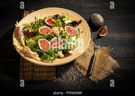 Gemischter Salat mit Feigen, Tomaten, Schafskäse, grissini mit Schinken auf Bambus Platte Stockfoto