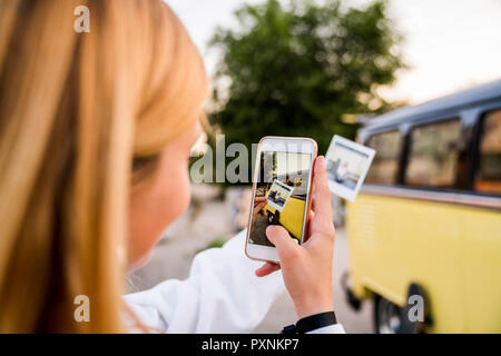 Junge Frau mit Handy Bild von Instant Foto bei einem Van Stockfoto