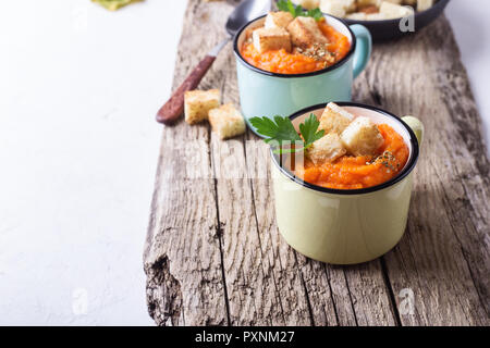 Herbst Kürbis Suppe auf hölzernen Tisch in ländlichen Tassen serviert, gesunde, vegetarische Mahlzeiten Stockfoto