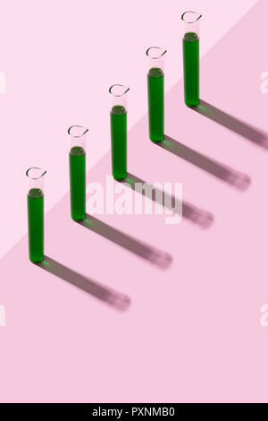 Reihe von Röhrchen mit Flüssigkeit, rosa Hintergrund Stockfoto