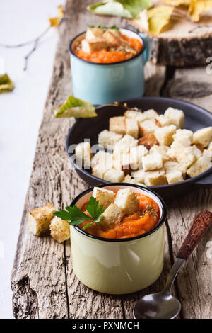 Herbst Kürbis Suppe auf hölzernen Tisch in ländlichen Tassen serviert, gesunde, vegetarische Mahlzeiten Stockfoto