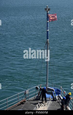 5 DUQM, Oman (12. Juni 2017) ein Seemann, der an Bord der Amphibischen dock Landung Schiff USS Carter Hall (LSD 50) wirft die First Navy Jack, während sie in den Hafen. Carter Hall, Teil der Bataan amphibischen bereit, Gruppe, ist in die USA 5 Flotte Bereich für Maßnahmen zur Erhöhung der Sicherheit im Seeverkehr im Einsatz Verbündeten und Partnern zu beruhigen, und der Freiheit der Schiffahrt und des freien Handels in der Region erhalten. Stockfoto