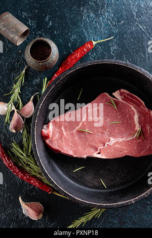 Rohes Rindfleisch Steak mit Gewürzen und Kräutern. Ansicht von oben. Stockfoto