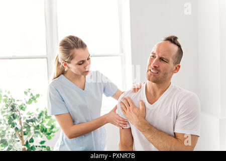 Männer erklären Schulterverletzung zum Arzt Stockfoto