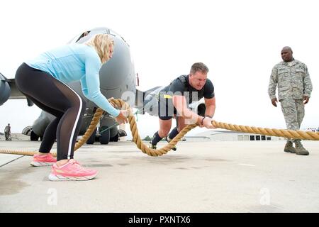 Cmdr. Grant Edwards, australische Bundespolizei, Botschaft von Australien, Washington, D.C., und nähert sich dem Ende seiner ersten Versuch an das Ziehen einer C-17 Globemaster III, 16. Juni 2017, auf Dover Air Force Base, Del Kate Lord, Edwards' Frau, Links, nimmt die überschüssige Seil für Bodenhaftung durch Edwards als Staff Sgt. Aaron Williams, 736Th Aircraft Maintenance Squadron Crew Chief, überwacht seine Sicherheit und Signale auf Luftfahrzeuge, die Betreuer für Bremsen und unterlegkeile am Ende seines ersten Versuch. Das Seil war an ein Zugfahrzeug angehängt. Stockfoto