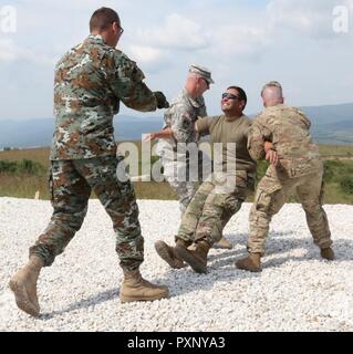 Kapitän Zoran Stankoski, ein Mazedonier, nicht-tödliche Waffen Instructor, Incapacitates US-Armee SPC. Trent Sagramsingh mit einer elektrischen Waffe am 15. Juni 2017 auf der South Base, Serbien während des Trainings als Teil der Platin Wolf. Diese Übung ist eine jährliche, zwei Woche Mission, die auf Friedenssicherung konzentriert. Stockfoto