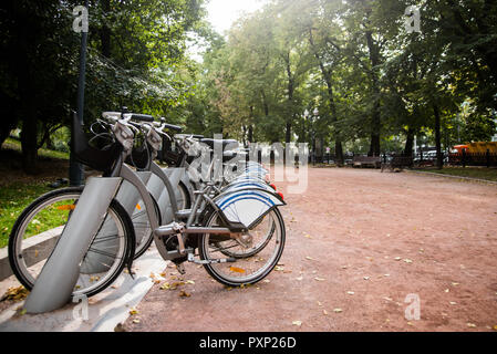 Fahrräder stehen in einer Reihe auf Parkplätze zu vermieten in der Stadt parken. Gesunde, ökologische Verkehrskonzept Stockfoto