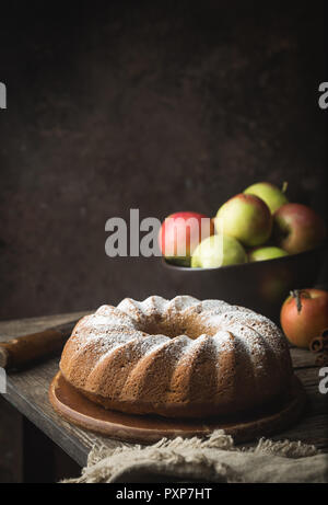 Landhausstil Apple Bundt Cake bestreut mit Puderzucker auf alten Holztisch Stockfoto