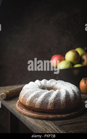 Landhausstil Apple Bundt Cake bestreut mit Puderzucker auf alten Holztisch Stockfoto