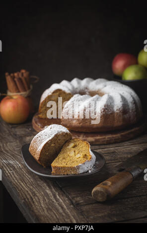 Landhausstil Apple Bundt Cake bestreut mit Puderzucker auf alten Holztisch Stockfoto