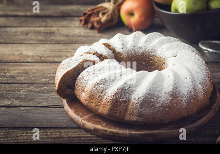 Landhausstil Apple Bundt Cake bestreut mit Puderzucker auf alten Holztisch Stockfoto