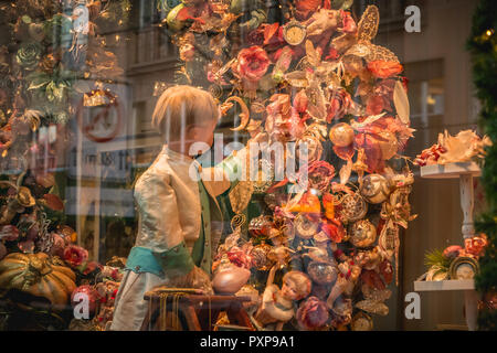 Basel, Schweiz, 25. Dezember 2017: Puppen und Spielzeug auf Anzeige im Spielzeugmuseum Fenster für Weihnachten mit Girlanden und Kugeln dekoriert Stockfoto