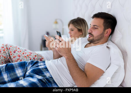 Bild von gelangweilten jungen Paares im Schlafzimmer Stockfoto