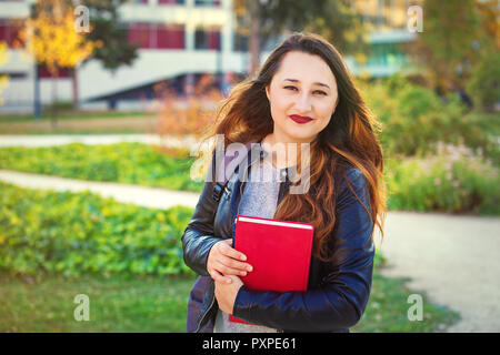 Junge Schüler Mädchen, dass Bücher in den Händen wandern in der Universität Garten. Stockfoto