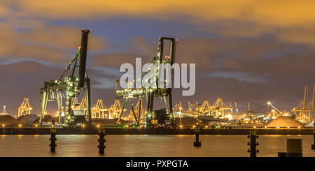 Industrielle Landschaft mit Harbour Quay und zwei ladekräne in der Nacht im Hafen von Rotterdam Europoort Maasvlakte Niederlande Stockfoto