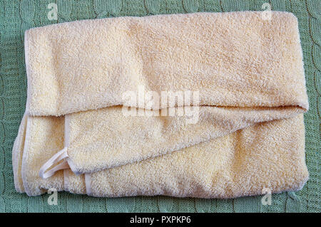 Terry gelb trockenen sauberen Handtuch liegen auf einem Wolle gestrickt Bett Bettdecke Stockfoto