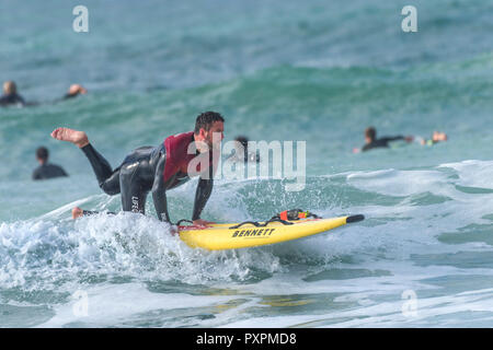 Surfen UK - Eine RNLI Rettungsschwimmer surfen auf ein lebensrettender surboard an Fistral Beach in Newquay in Cornwall. Stockfoto