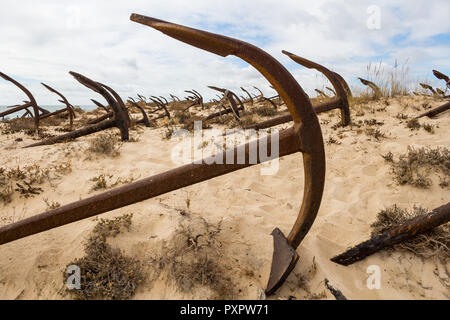 Detail eines viele Anker am Anker Friedhof, an der Küste des Atlantik auf den Dünen. Bewölkter Himmel. Tavira, Portugal. Stockfoto