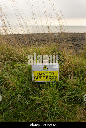 Gelb und weiß Gefahr Klippenrand Zeichen auf wales Küstenweg, Küstenerosion in der Nähe von Pwllheli Nord-wales großbritannien Stockfoto