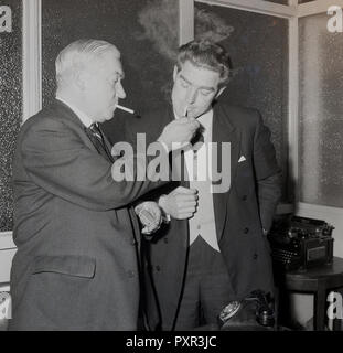 1956, historische, in einem Glas-Fenster Zimmer im Millwall FC, der Vorsitzende, der kis Rauchen, begrüßt den neuen Manager des Clubs, Ron Grau durch Beleuchtung seine Zigarette, Millwall Football Club, New Cross, London, SE14, England, UK. Stockfoto