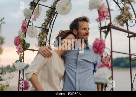 Glückliches Paar umarmt unter Hochzeit arch Stockfoto