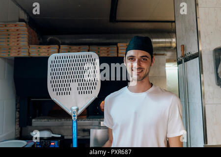 Portrait von lächelnden Pizza Bäcker Holding pizza Peel in der Küche Stockfoto