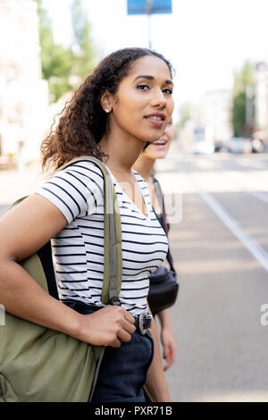 Zwei junge Frauen überschreiten Straße in der Stadt Stockfoto