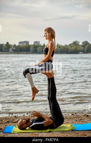 Junger Mann und Frau praktizieren Acro Yoga Stockfoto