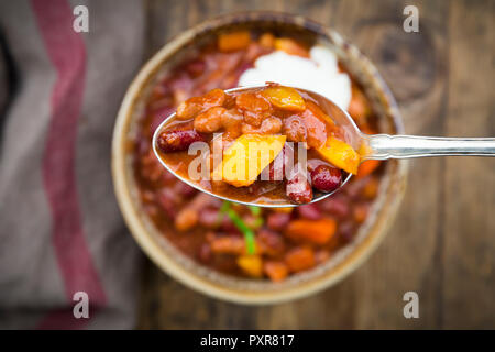 Chili con Carne mit Koriander und saurer Sahne, Löffel, close-up Stockfoto