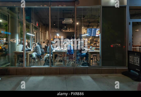 Kunden profitieren Sie von kostenlosem wi-fi in einem Café in Chelsea in New York am Dienstag, den 16. Oktober 2018. Das kostenlose Wi-fi und der gemeinschaftliche Tabellen regen die Nutzung der Coffee Shop als Arbeitsbereich. (Â© Richard B. Levine) Stockfoto