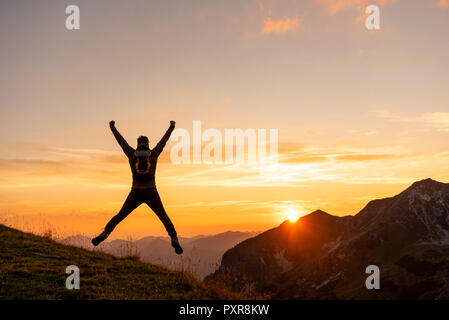 Deutschland, Bayern, Oberstdorf, Mann auf eine Wanderung in die Berge bei Sonnenuntergang springen Stockfoto