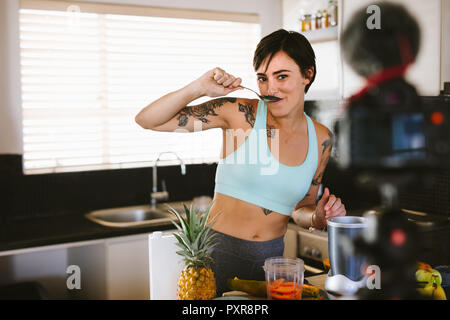 Passen junge Frau testen Smoothie und Kamera. Frauen Lebensmittel vlogger Aufnahme eines Videos auf Kamera für Ihr on-line-Kanal. Stockfoto
