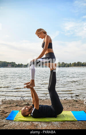 Junger Mann und Frau praktizieren Acro Yoga Stockfoto