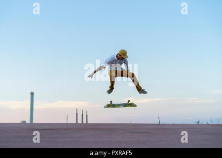 Junger Mann, ein Skateboard Trick auf eine Spur in der Dämmerung Stockfoto