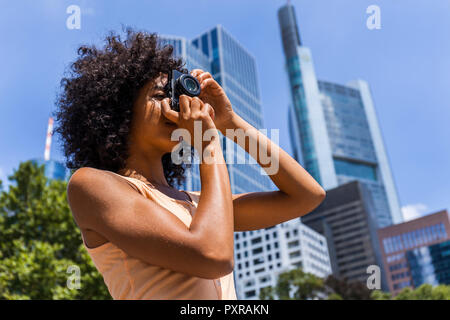 Deutschland, Frankfurt, junge Frau mit dem lockigen Haar Fotos nehmen in der Stadt Stockfoto