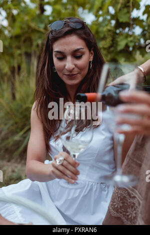 Frau gießen Wein im Glas auf ein Picknick in der Natur Stockfoto