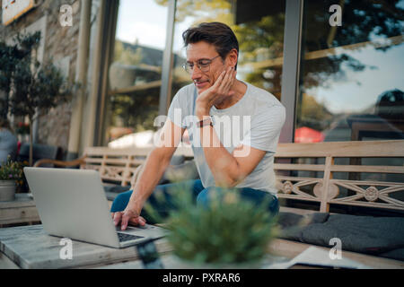 Reifen Geschäftsmann im Café sitzen, mit Laptop Stockfoto