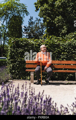 Älterer Mann sitzt auf einer Parkbank und wartet Stockfoto