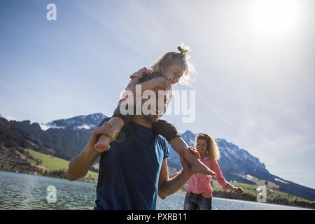 Österreich, Tirol, Walchsee, happy Vater die Tochter auf den Schultern am See Stockfoto