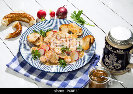 Weißwurst Salat mit gerösteten Brezel Brötchen, süßem Senf, Brezeln, rote Radieschen und Bierkrug Stockfoto