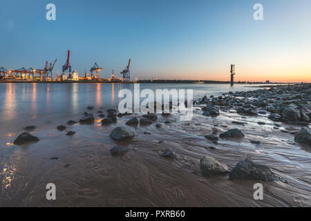 Deutschland, Hamburg, Baum, Elbe Strand am Abend, Container Hafen im Hintergrund Stockfoto