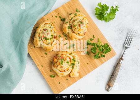 Sticky Buns mit Feta, Käse, Speck und Petersilie auf Holzbrett Stockfoto