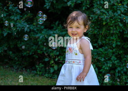 Portrait von lächelnden Mädchen mit Seifenblasen im Garten Stockfoto