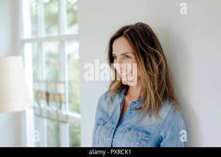 Portrait von lächelnden reife Frau zu Hause lehnte sich gegen eine Wand. Stockfoto