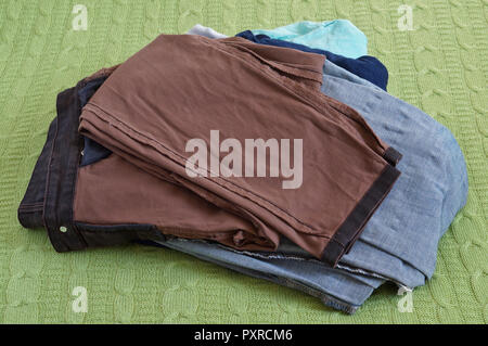 Einen Stapel sauber gewaschen Damen Jeans Hose lag auf einem grünen Bett wolle. Stockfoto