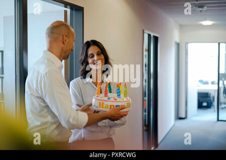 Geschäftsmann gifting sein Kollege mit einem Geburtstagskuchen im Büro Stockfoto